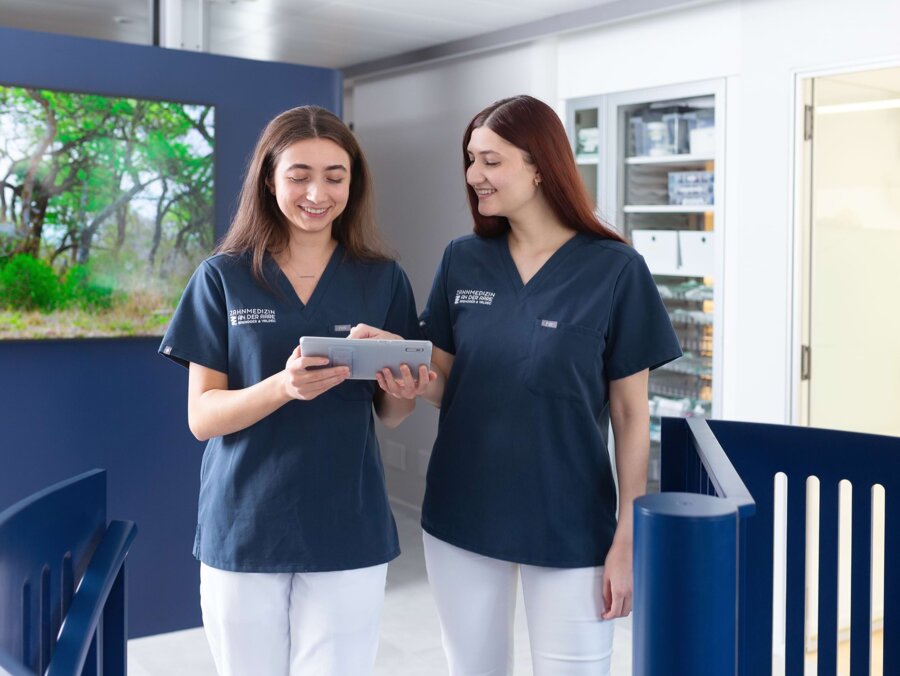 Zwei Teammitglieder laufen durch die Praxis und schauen zusammen auf ein Tablet.