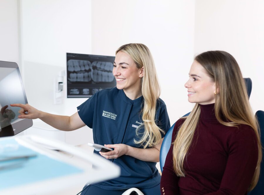 Dr. Daniela Brüngger zeigt einer Patientin im Behandlungszimmer etwas auf einem Bildschirm.