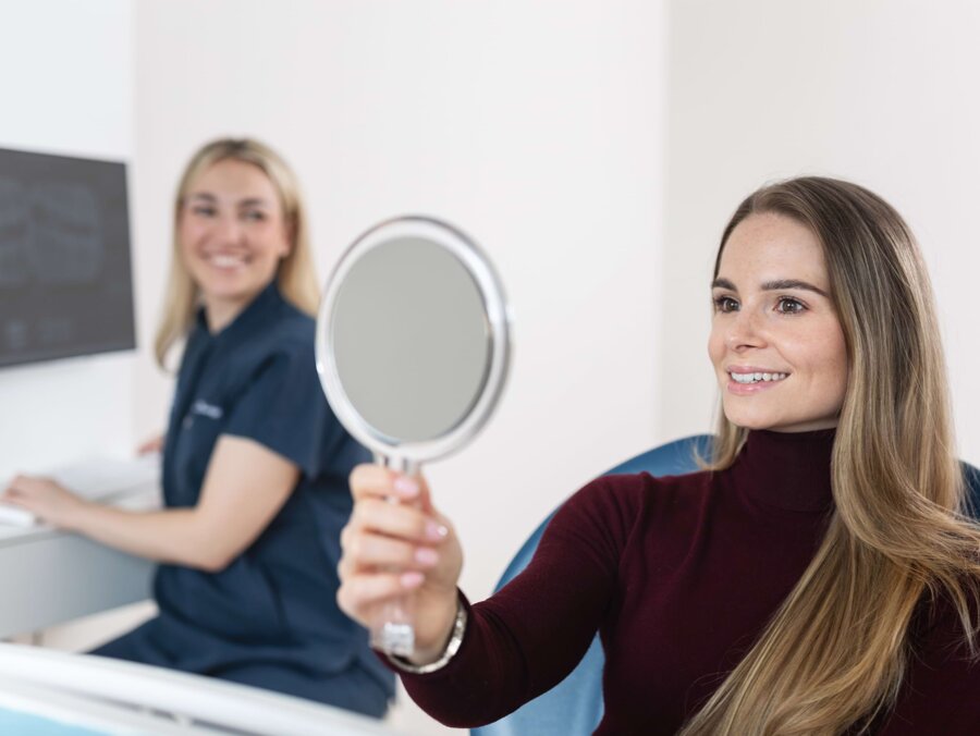 Eine Patientin betrachtet sich nach der Behandlung im Handspiegel.